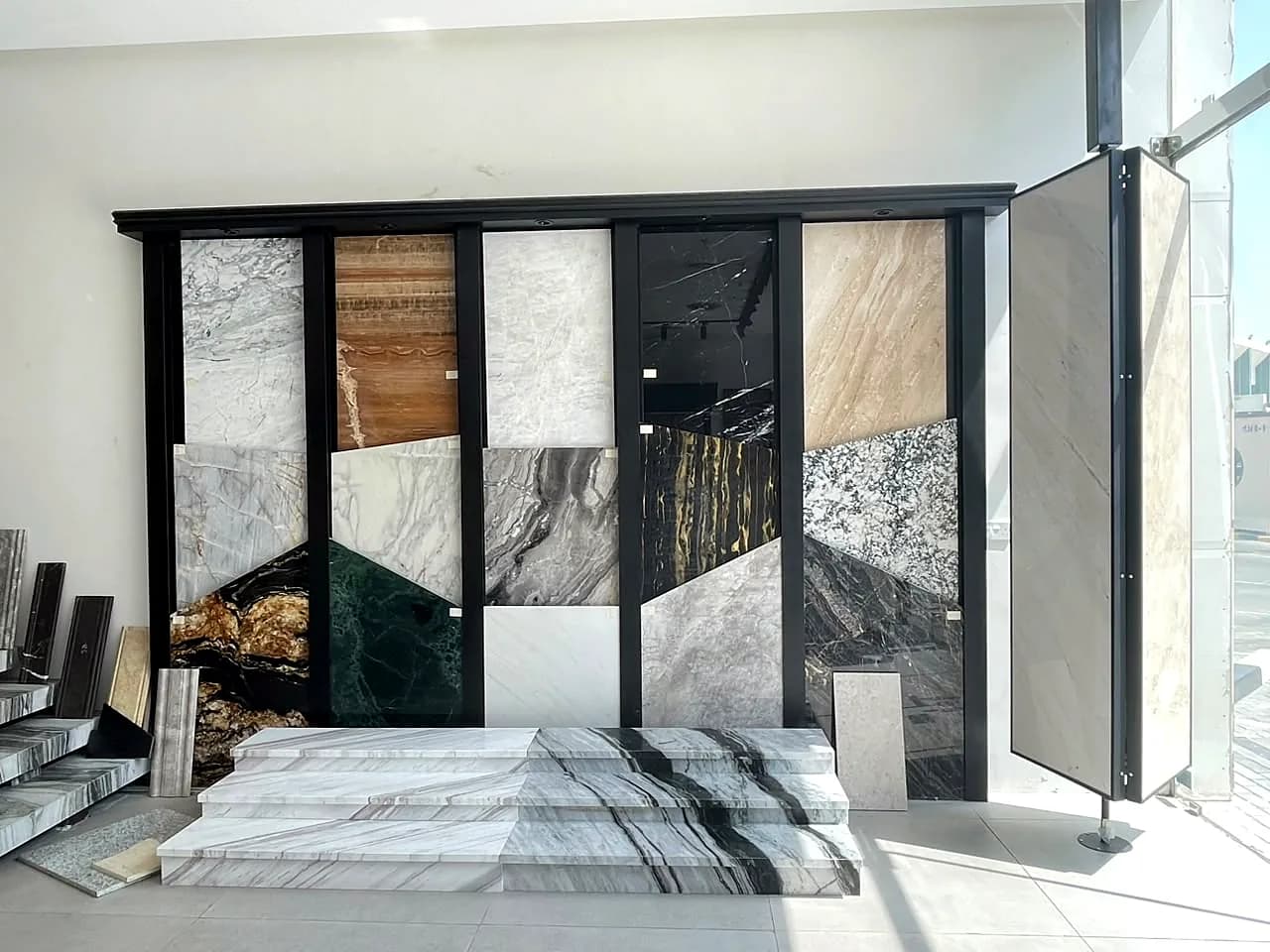 Showroom sample wall with white, grey, green, black and onyx stone, and white marble steps
