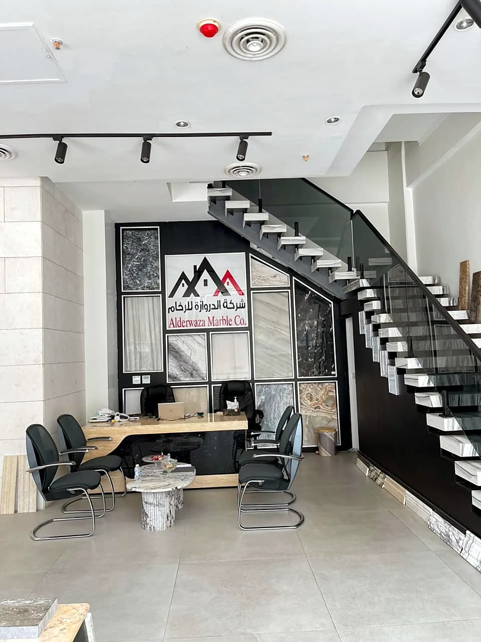 Reception desk in front of the Alderwaza Marble Co. logo and stone sample wall