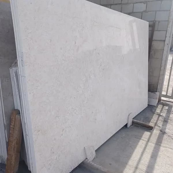 Polished beige Omani marble slab standing in the stone yard
