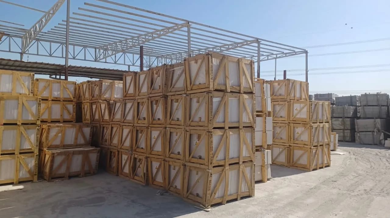 Rows of crated marble tiles under the steel canopy of the Amgara stone yard